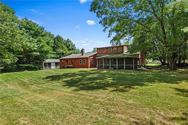 rear view of house featuring a sunroom and a yard