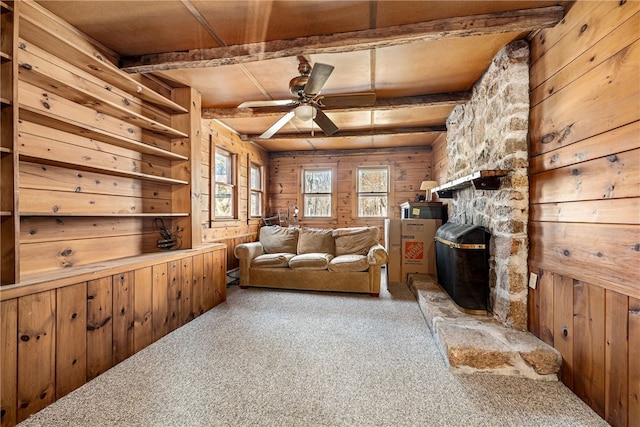 living room with wood walls, beamed ceiling, and carpet flooring