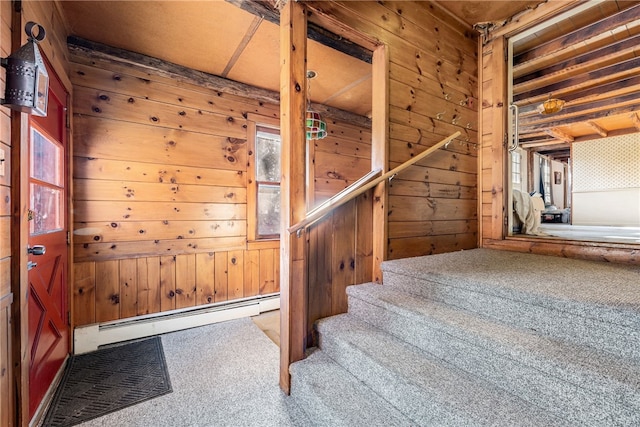 stairs featuring a baseboard radiator, wooden walls, and carpet flooring