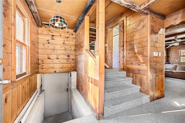 staircase with plenty of natural light, carpet, and wood walls