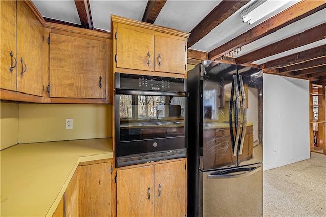 kitchen featuring light colored carpet, beamed ceiling, double oven, and fridge