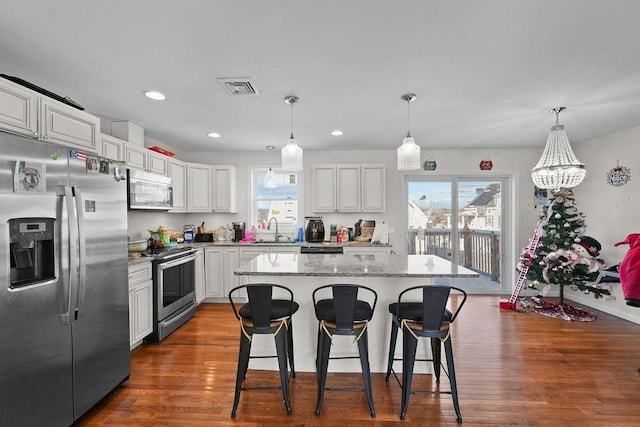 kitchen with white cabinetry, hanging light fixtures, and stainless steel appliances