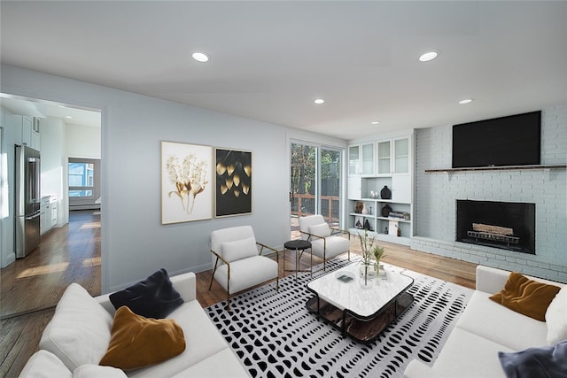 living room featuring a brick fireplace, recessed lighting, wood finished floors, and a healthy amount of sunlight