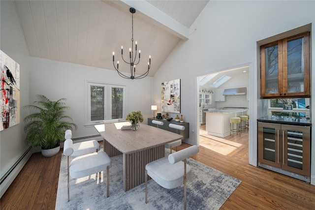 dining space with a notable chandelier, beamed ceiling, a baseboard heating unit, and wood finished floors