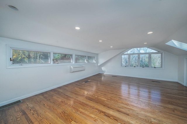 bonus room featuring lofted ceiling with skylight, wood finished floors, and baseboards