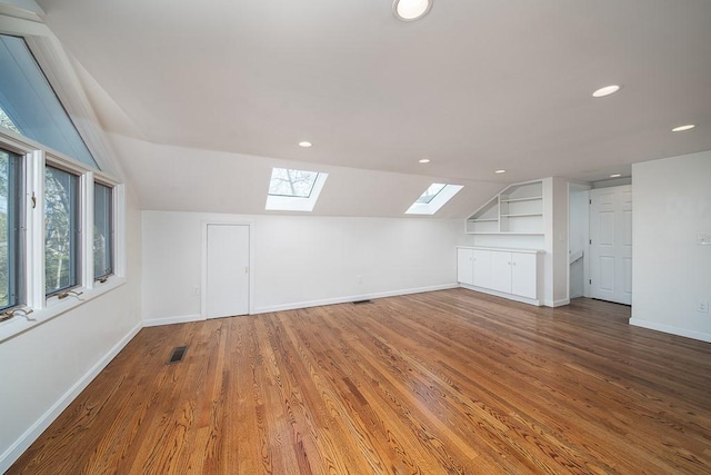 bonus room featuring visible vents, wood finished floors, recessed lighting, vaulted ceiling with skylight, and baseboards