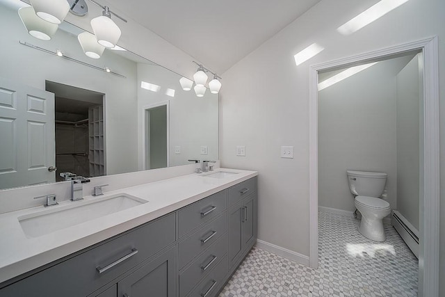 bathroom featuring lofted ceiling, toilet, a baseboard radiator, and a sink