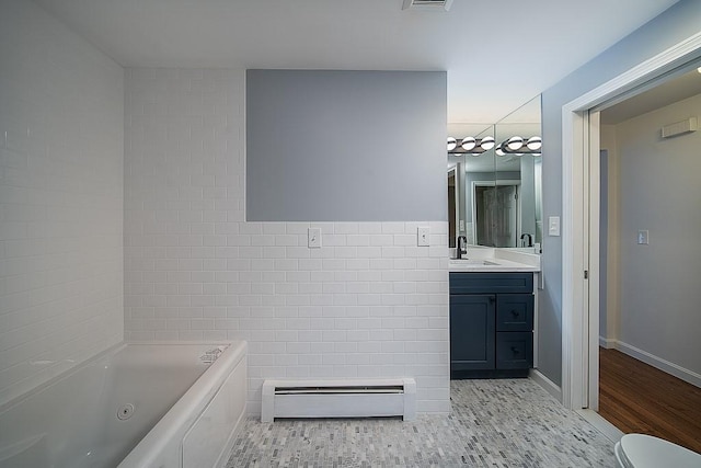 full bath featuring visible vents, vanity, a whirlpool tub, tile walls, and a baseboard radiator