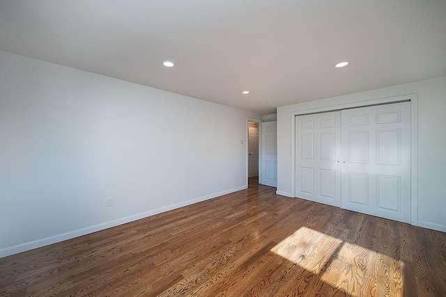 unfurnished bedroom featuring recessed lighting, wood finished floors, baseboards, and a closet