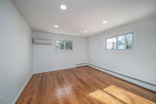 unfurnished room featuring wood finished floors, baseboards, a wall mounted AC, recessed lighting, and baseboard heating