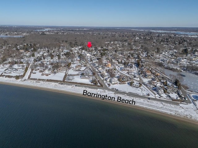 snowy aerial view featuring a water view and a beach view