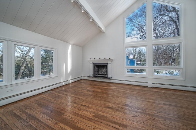 unfurnished living room featuring wood finished floors, a healthy amount of sunlight, a fireplace with raised hearth, and track lighting