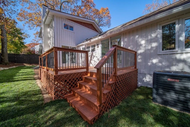 back of house with board and batten siding, fence, central AC, a yard, and a deck