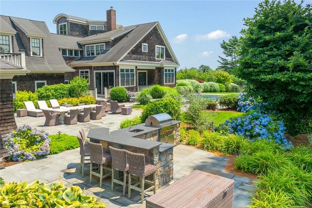 rear view of property with a patio, area for grilling, and a bar