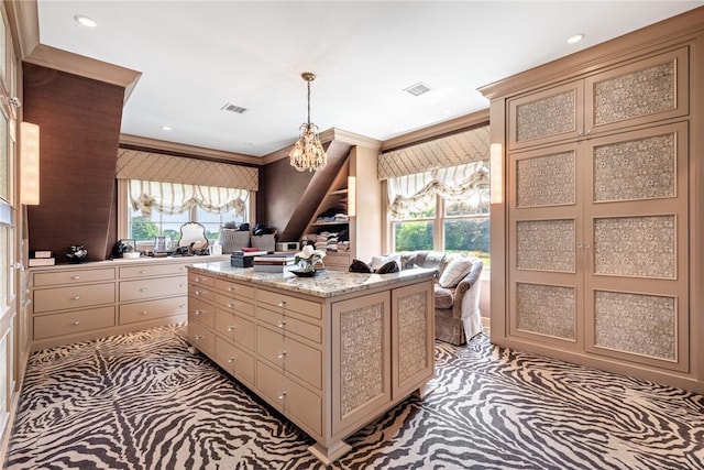 kitchen with hanging light fixtures, crown molding, light colored carpet, and a kitchen island