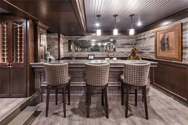 bar featuring pendant lighting, wood ceiling, wooden walls, and dark brown cabinets