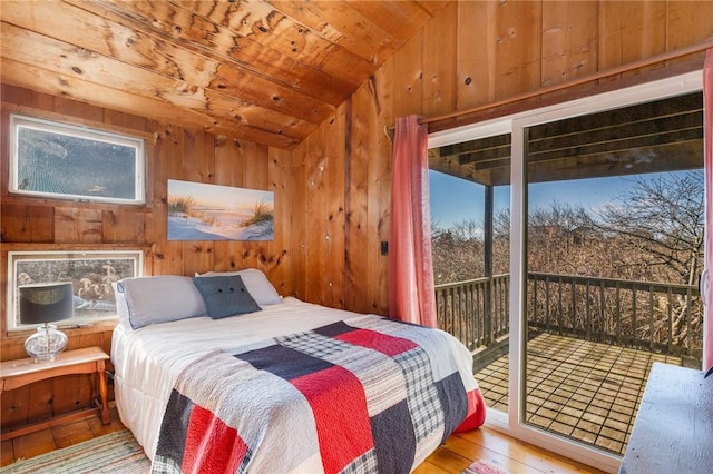 bedroom featuring lofted ceiling, wooden ceiling, wooden walls, access to exterior, and hardwood / wood-style floors