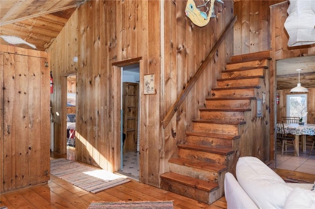 stairway featuring hardwood / wood-style flooring, lofted ceiling, and wooden walls