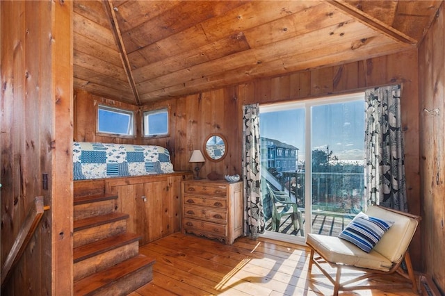 living area with lofted ceiling, wooden ceiling, light hardwood / wood-style flooring, and wood walls