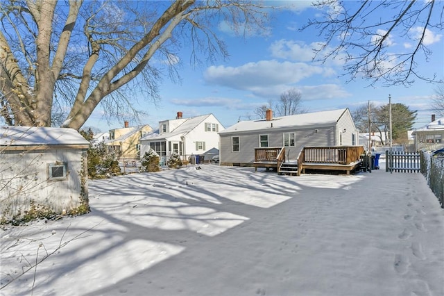 snow covered back of property with a wooden deck