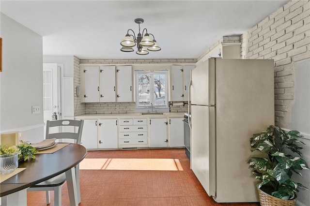 kitchen with sink, decorative light fixtures, white refrigerator, decorative backsplash, and white cabinets