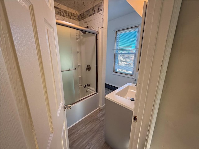 bathroom with vanity, hardwood / wood-style flooring, and bath / shower combo with glass door