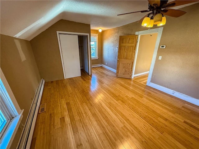 bonus room with baseboard heating, lofted ceiling, a textured ceiling, and light hardwood / wood-style flooring