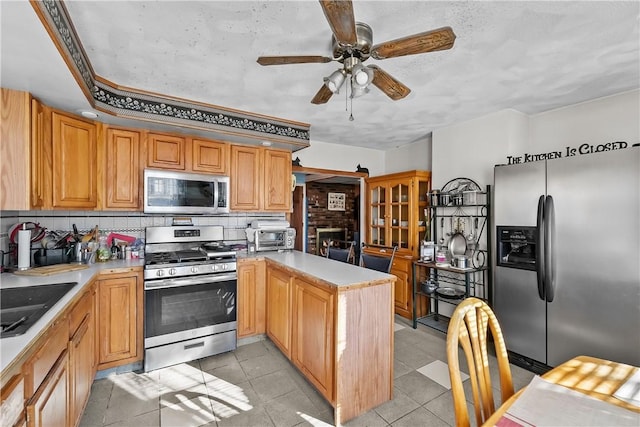 kitchen with sink, tasteful backsplash, kitchen peninsula, ceiling fan, and stainless steel appliances