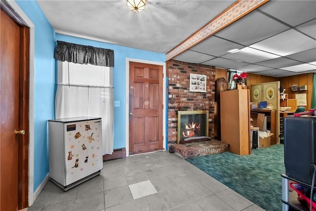 carpeted living room featuring a fireplace and wooden walls