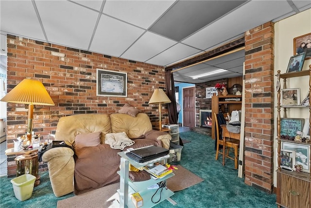 living room featuring a paneled ceiling, brick wall, and dark colored carpet