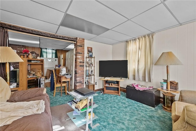 living room featuring wooden walls, carpet flooring, and a drop ceiling