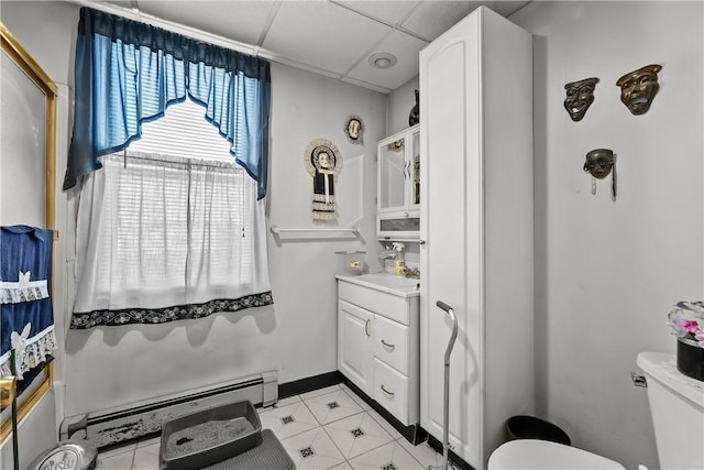 bathroom featuring vanity, a baseboard heating unit, walk in shower, toilet, and a drop ceiling