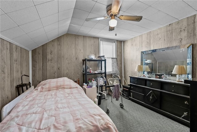 bedroom with vaulted ceiling, carpet floors, wooden walls, and ceiling fan