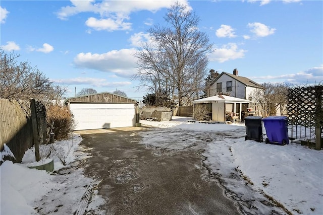 yard layered in snow featuring an outbuilding and a garage