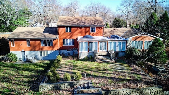 back of property with a sunroom and a lawn