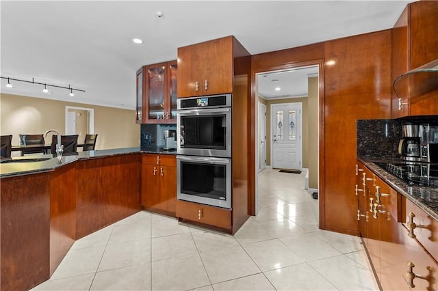 kitchen with light tile patterned floors, sink, double oven, black stovetop, and decorative backsplash