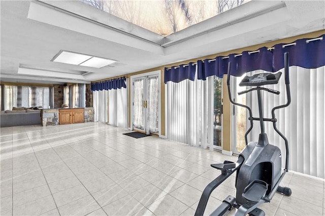 exercise room featuring a raised ceiling, tile patterned flooring, and french doors