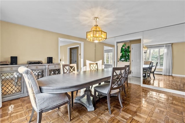 dining room featuring a notable chandelier and parquet flooring