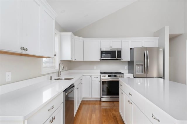 kitchen featuring lofted ceiling, sink, white cabinets, and appliances with stainless steel finishes