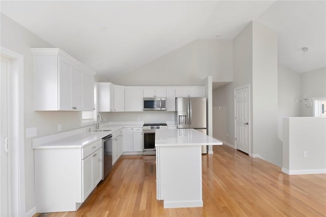 kitchen with sink, white cabinetry, stainless steel appliances, a center island, and high vaulted ceiling