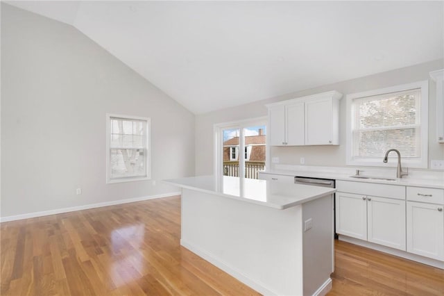 kitchen with lofted ceiling, sink, a center island, light hardwood / wood-style floors, and white cabinets