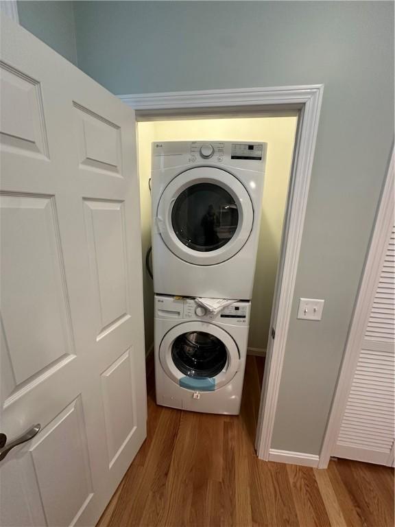 clothes washing area with stacked washer / dryer and hardwood / wood-style flooring