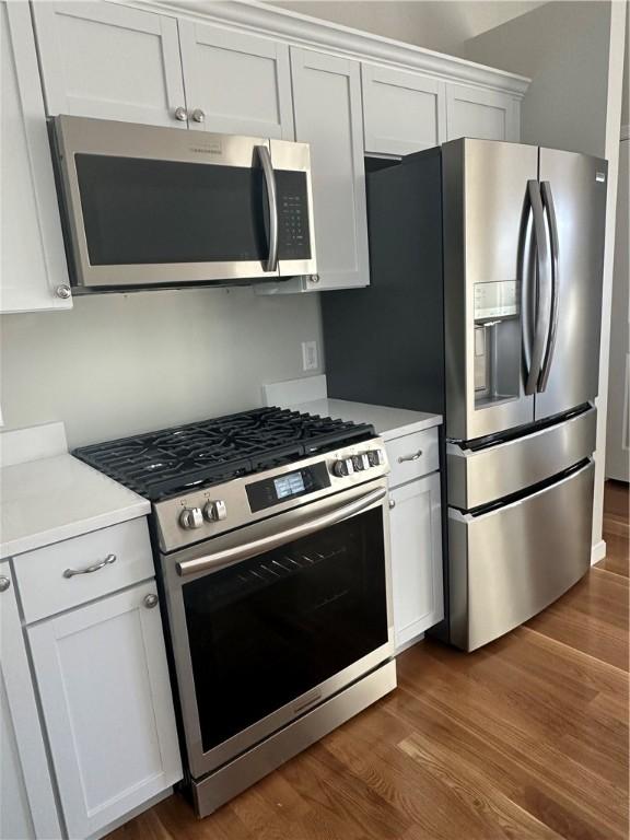 kitchen featuring stainless steel appliances, dark hardwood / wood-style flooring, and white cabinets