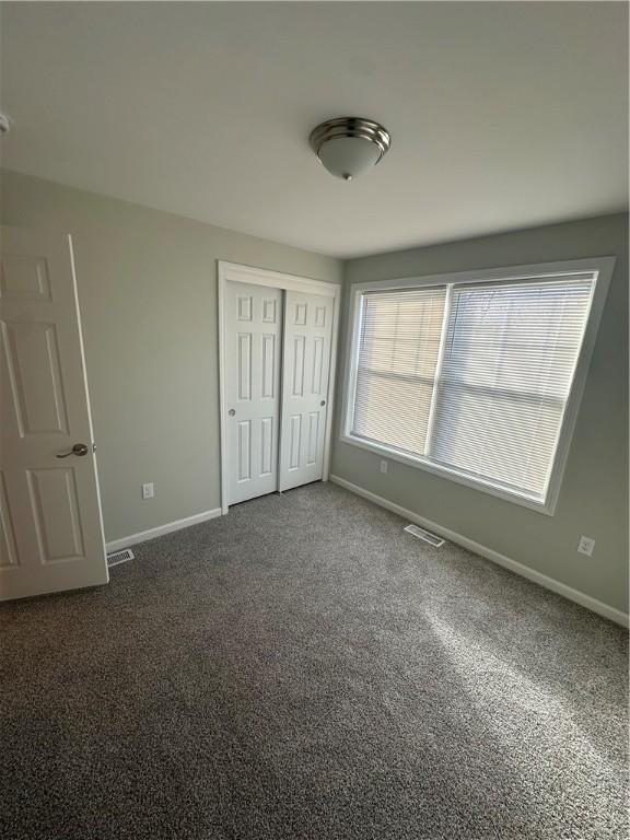 unfurnished bedroom featuring dark carpet and a closet