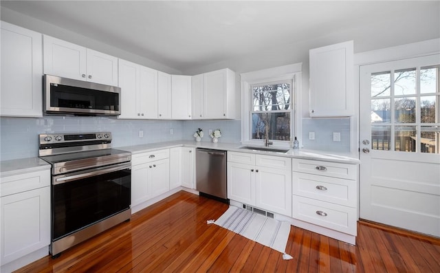 kitchen featuring sink, plenty of natural light, appliances with stainless steel finishes, dark hardwood / wood-style flooring, and white cabinets