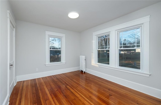 empty room featuring radiator and hardwood / wood-style floors