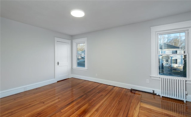 empty room featuring radiator, hardwood / wood-style flooring, and a healthy amount of sunlight