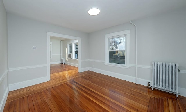 empty room featuring radiator and hardwood / wood-style flooring