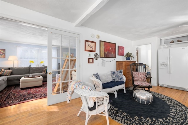 living room featuring beam ceiling, hardwood / wood-style flooring, and french doors