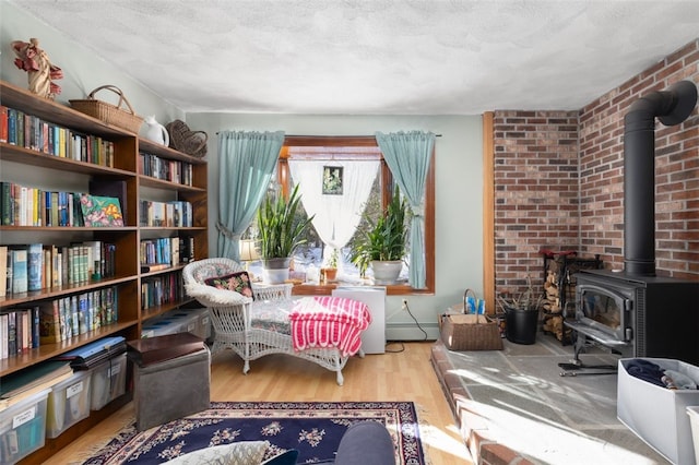 sitting room with light hardwood / wood-style flooring, a textured ceiling, and a wood stove